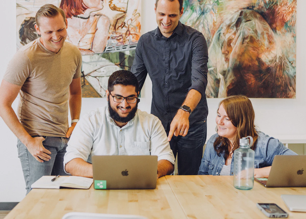Equipe jovem sorrindo em volta de um notebook